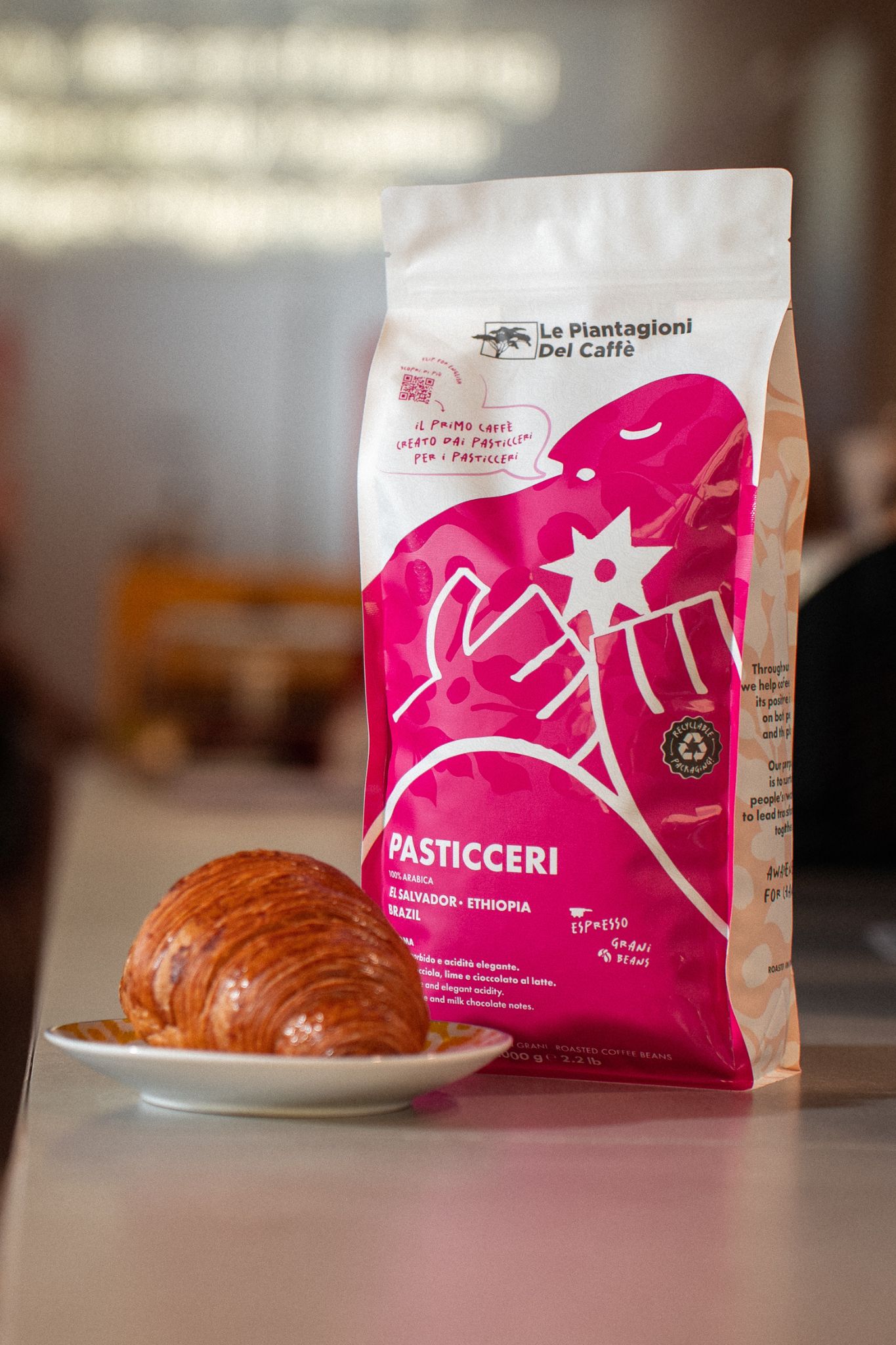 pacco di caffè speciality brand PASTICCERI su un bancone di una caffetteria con una brioche accanto